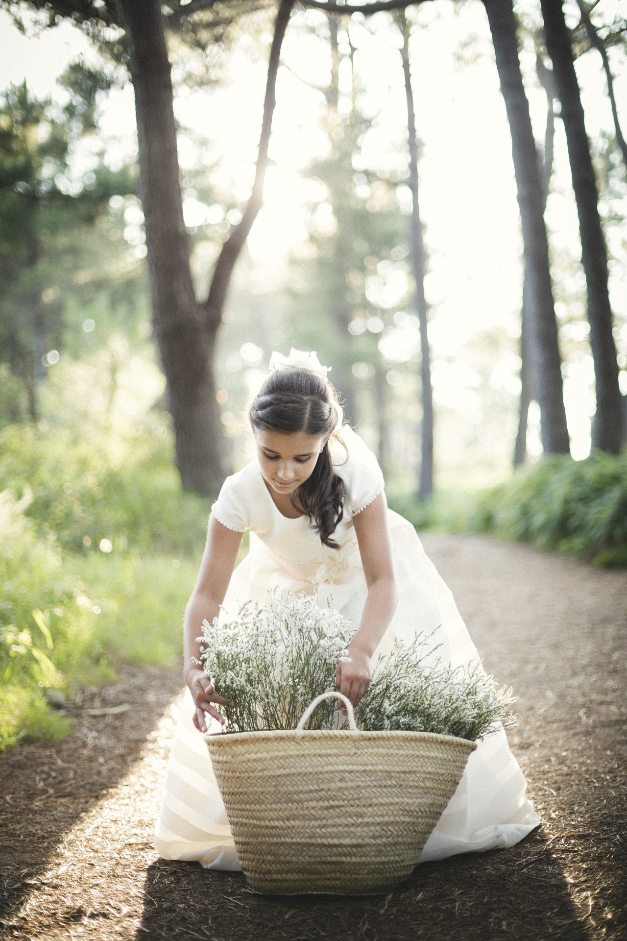 niña con vestido de comunión cogiendo un cesto de flores en una sesión fotográfica de comunión en Pontevedra, Galicia